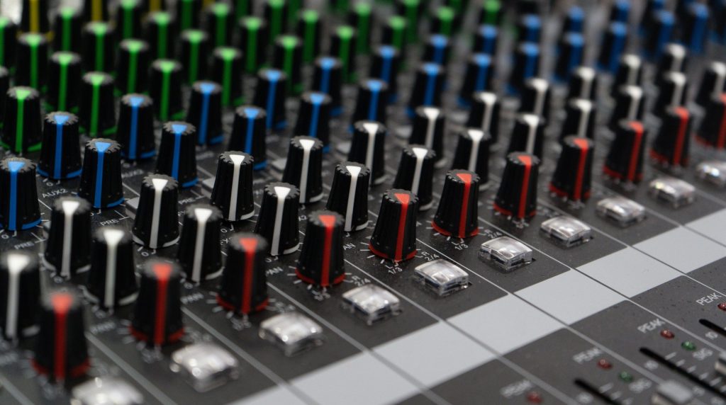 Detailed view of colorful dials on an audio mixing console, showcasing sound control technology.